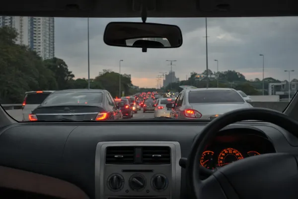 Evening stop-go traffic on a Malaysian city highway, seen from the driver’s seat of a right-hand-drive car