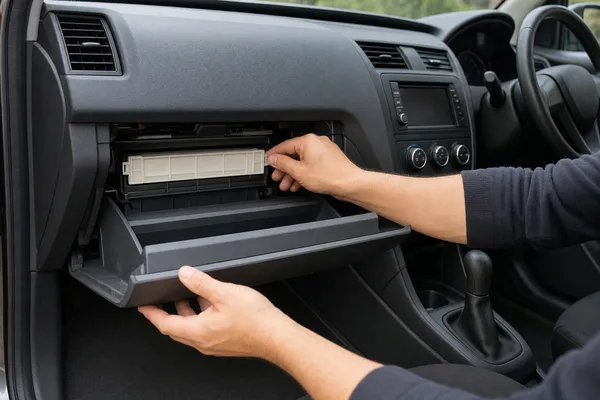 The glovebox of a right-hand-drive car lowered to show the cabin filter cover behind it